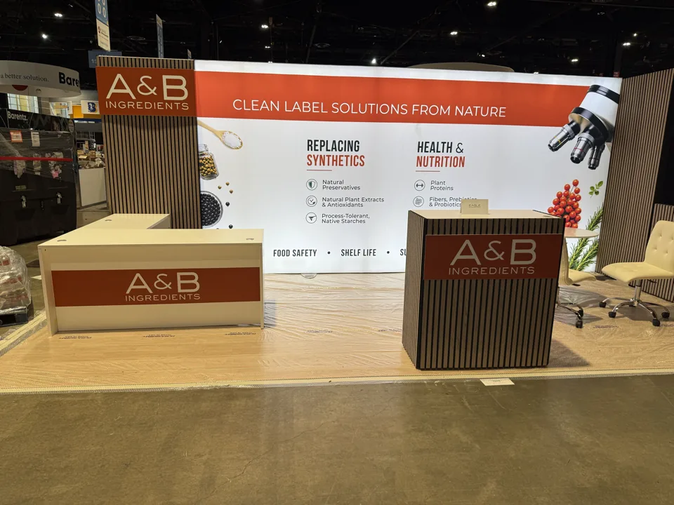 A&B Ingredients exhibit with a wide orange and white graphic wall and timber counters