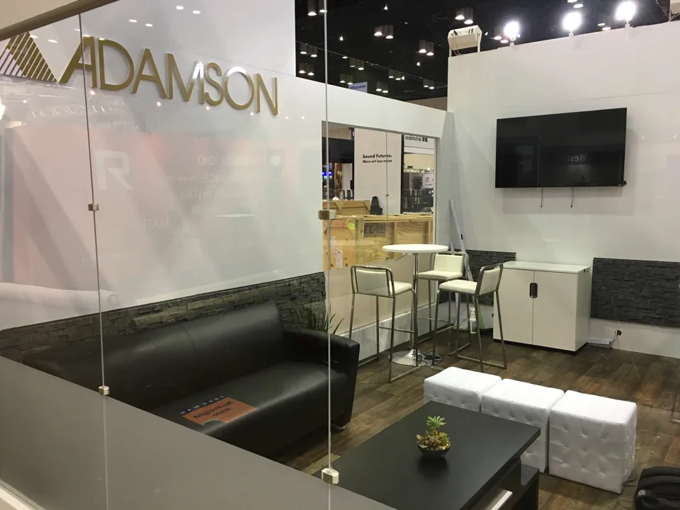 Adamson exhibit lounge with black sofa and glass meeting wall