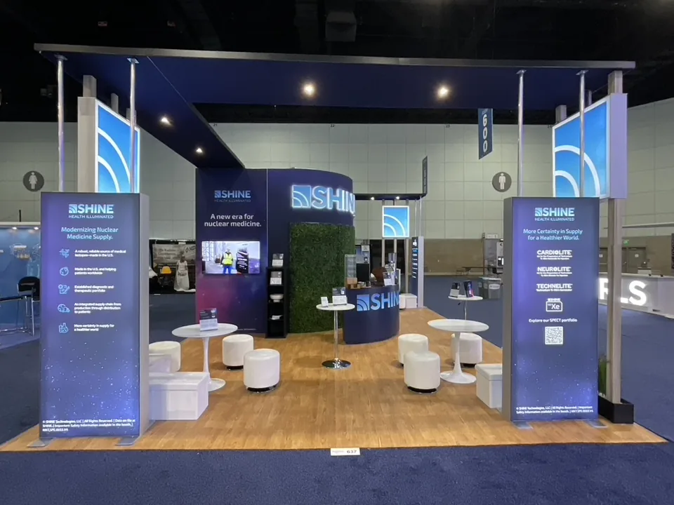 Shine exhibit with blue graphic towers, wood floor and white lounge seating