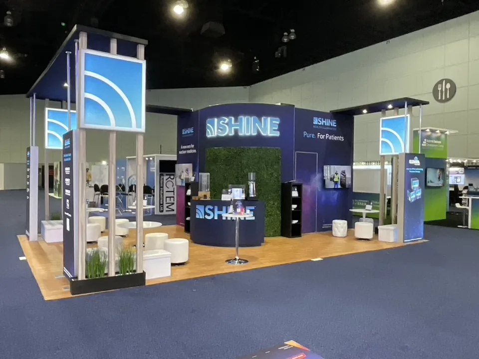 Shine exhibit with overhead sign, green wall and round tables