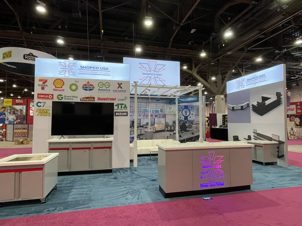 Shopco USA exhibit with overhead sign, white pergola and product displays