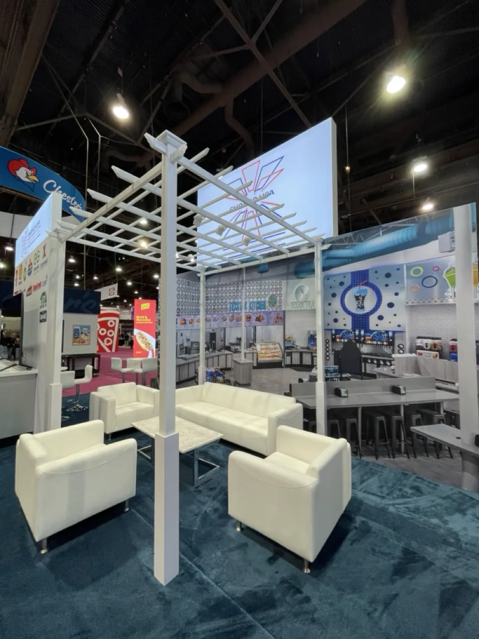 Shopco USA exhibit with white pergola and lounge seating