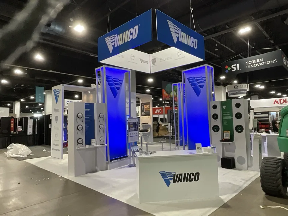 Vanco exhibit with blue hanging signs and illuminated towers